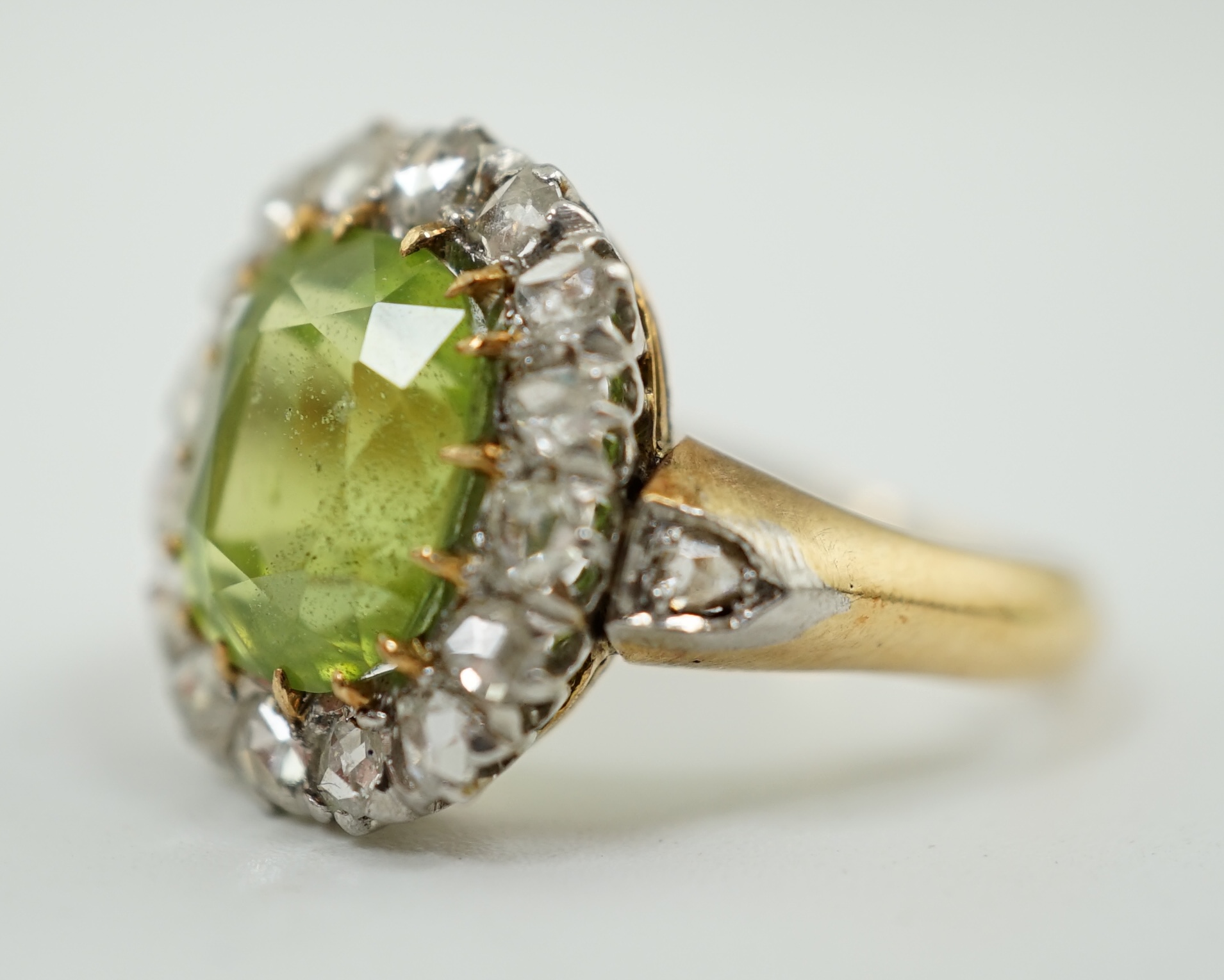 An early 20th century gold, peridot and diamond set oval cluster ring